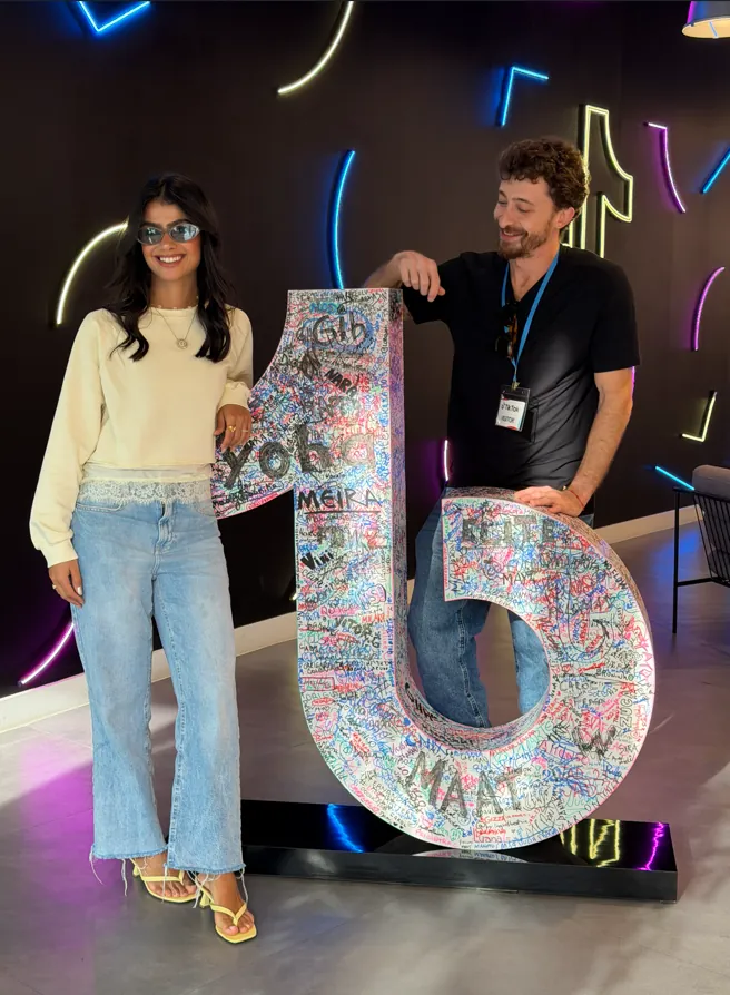 Ana Coutinho no escritório do TikTok ao lado do logo assinado por creators